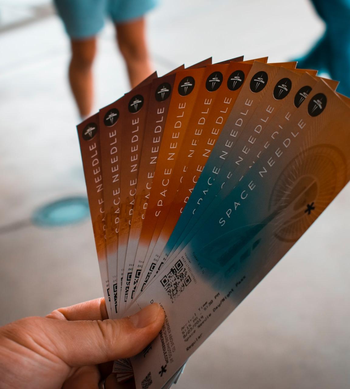 person holding brown, blue, and white tickets