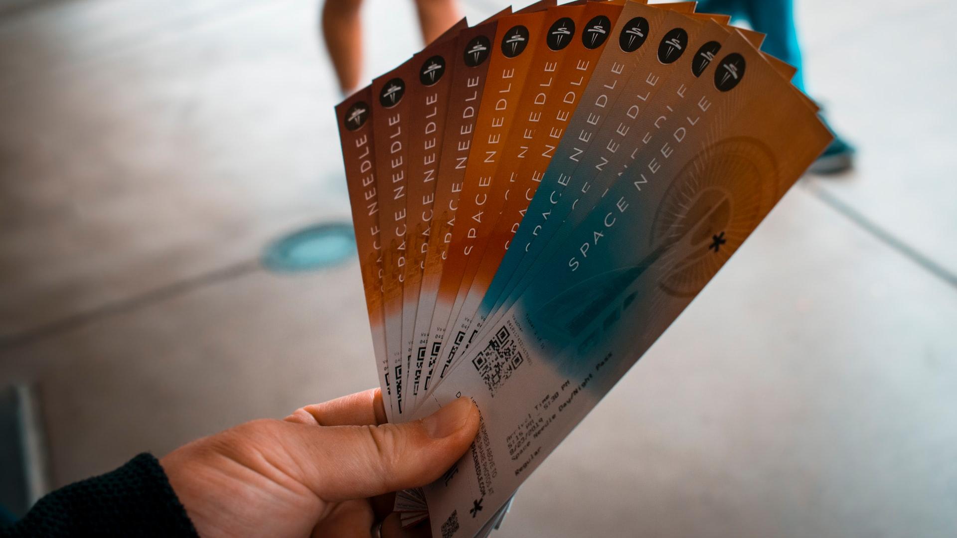 person holding brown, blue, and white tickets